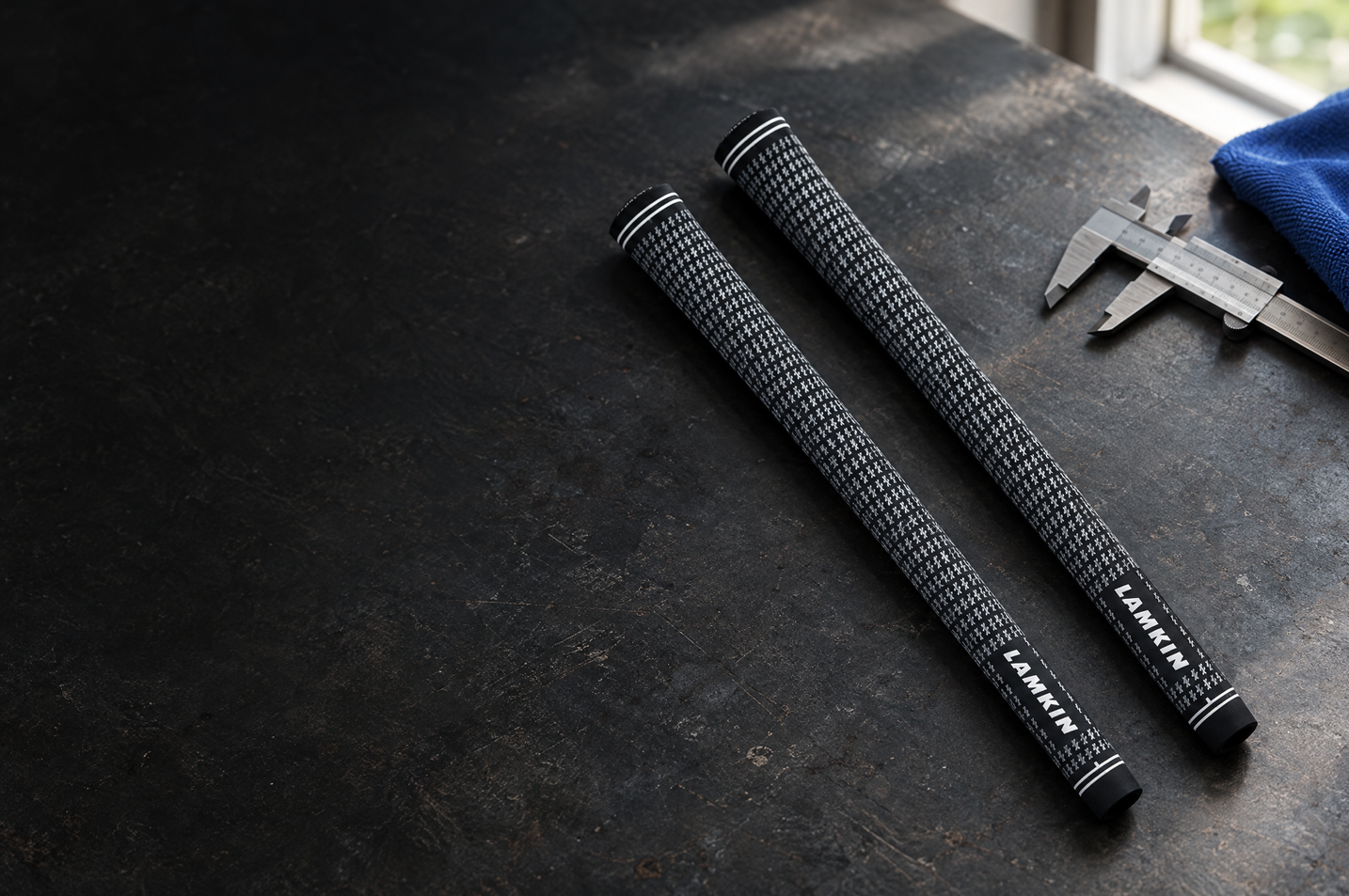 Two Lamkin golf grips beside a calliper on a workshop bench